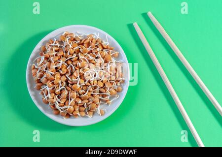 piatto con germogli di lenticchie e bastoncini su sfondo verde Foto Stock