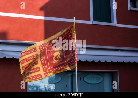 Bandiera della Repubblica di Venezia con un edificio rosso sullo sfondo Foto Stock