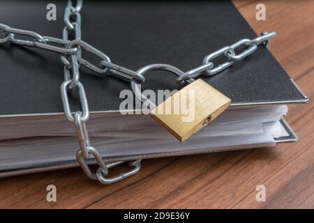 File e documenti riservati in rilegatore con lucchetto e catena. Concetto di privacy e sicurezza. Foto Stock