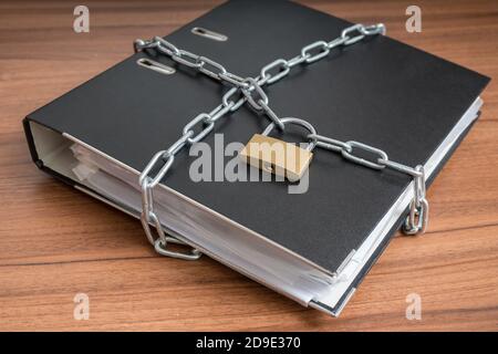 File e documenti riservati in rilegatore con lucchetto e catena. Concetto di privacy e sicurezza. Foto Stock