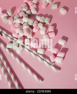 Marshmallow pastello multicolore e cannucce di carta eco-friendly per bevande su sfondo rosa. Foto Stock