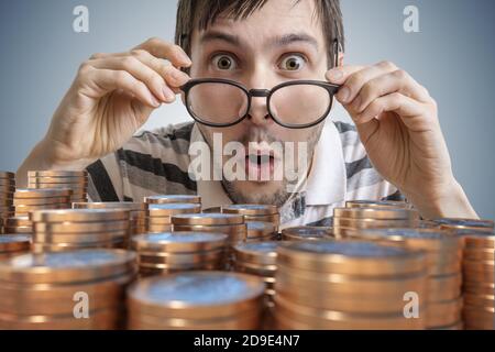 L'uomo giovane sorpreso vince i soldi. Molte monete di fronte. Foto Stock
