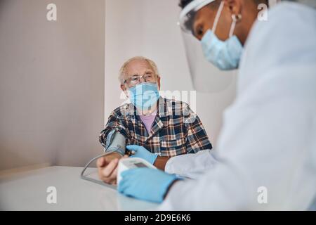 Medico concentrato che misura la pressione sanguigna del paziente Foto Stock