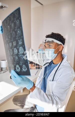 Neurologo che analizza le immagini cerebrali di un uomo anziano Foto Stock