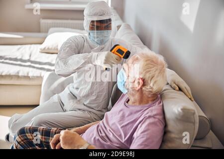 Medico geriatrico che misura la temperatura di un paziente Foto Stock