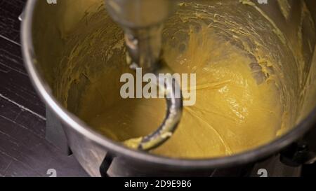 La miscelazione di impasti per la cottura del pane con impastatrice professionale a spirale in corrispondenza della macchina di produzione. La pasta è impastata per gli hamburger. Foto Stock