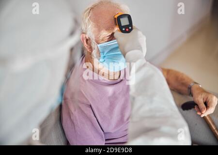 Medico che utilizza un termometro a infrarossi per la misurazione della temperatura Foto Stock