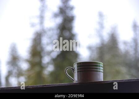 Il caffè del mattino si affaccia sugli spruces verdi con la prima neve dentro le montagne Foto Stock
