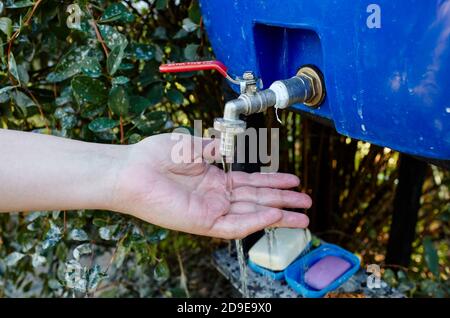 Lavaggio delle mani. Donna lava le mani sotto il rubinetto d'estate in giardino. Prevenzione pandemica del coronavirus lavarsi le mani con acqua di sapone Foto Stock