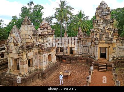 Viaggiatore femminile guardando in su alle rovine dell'antico tempio Khmer di Prasat Swok Kok Thom, provincia di SA Kaeo, Thailandia Foto Stock