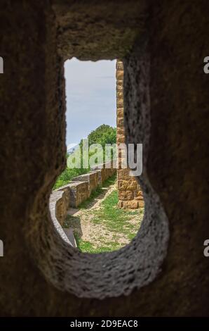 Vista attraverso una scappatoia in un muro del castello a parti del complesso esterno del castello. Foto Stock