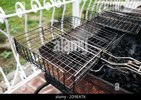 Vista della terrazza all'aperto con barbecue nel cortile esterno. Attrezzatura da cucina sporca vuota. Griglia nera con carbone. Non è prevista la celebrazione del barbecue durante la pandemia. Foto Stock