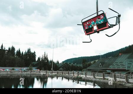 Bukovel, Ucraina - Luglio 2020: Seggiovia vuota che salirà in estate in una popolare stazione sciistica Ucraina Bukovel. Bellissimo lago e montagne Carpazi. Foto Stock