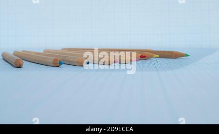 Matite di legno con conduttori colorati su carta squadrata blu. Oggetti sfocati. Spazio di copia per il testo. Foto Stock