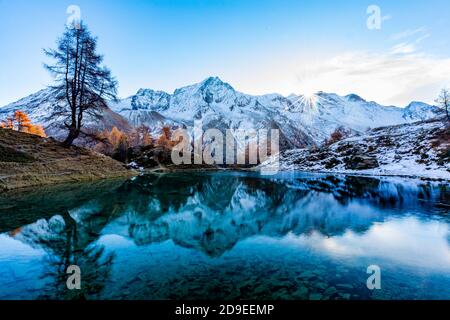 Riflessi di montagne innevate in un lago ghiacciato blu in montagna Foto Stock