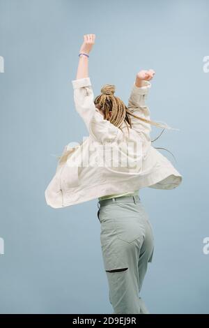 Festeggia la giovane donna con trecce afro bionde eleganti da dietro su blu Foto Stock