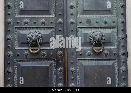 Antico anello di pomolo in bronzo della porta a forma di leone su una vecchia porta. Foto Stock