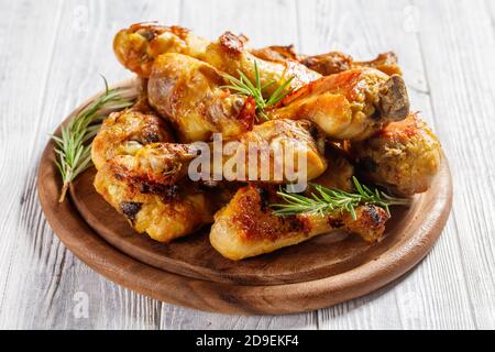 Bastoncini di pollo serviti su un tagliere di legno su uno sfondo di legno bianco con sprigg di rosmarino fresco, vista dall'alto, primo piano Foto Stock