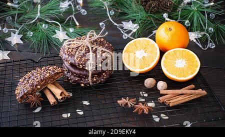L'avvento e l'umore di Natale, Elisenlebkuchen con glassa di cioccolato e nocciole, splendidamente decorato su un tavolo di legno scuro sullo sfondo Foto Stock