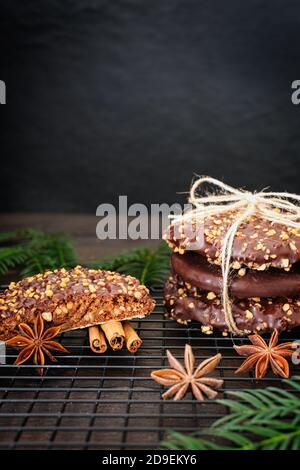 L'avvento e l'umore di Natale, Elisenlebkuchen con glassa di cioccolato e nocciole, splendidamente decorato su un tavolo di legno scuro sullo sfondo Foto Stock