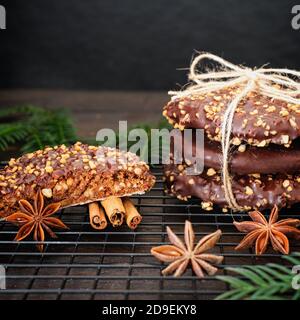 L'avvento e l'umore di Natale, Elisenlebkuchen con glassa di cioccolato e nocciole, splendidamente decorato su un tavolo di legno scuro sullo sfondo Foto Stock