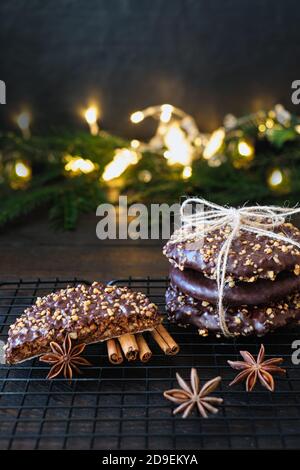 L'avvento e l'umore di Natale, Elisenlebkuchen con glassa di cioccolato e nocciole, splendidamente decorato su un tavolo di legno scuro sullo sfondo Foto Stock