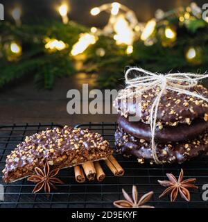 L'avvento e l'umore di Natale, Elisenlebkuchen con glassa di cioccolato e nocciole, splendidamente decorato su un tavolo di legno scuro sullo sfondo Foto Stock