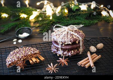 L'avvento e l'umore di Natale, Elisenlebkuchen con glassa di cioccolato e nocciole, splendidamente decorato su un tavolo di legno scuro sullo sfondo Foto Stock