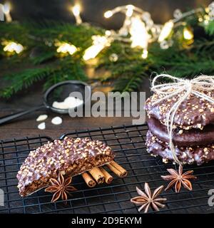 L'avvento e l'umore di Natale, Elisenlebkuchen con glassa di cioccolato e nocciole, splendidamente decorato su un tavolo di legno scuro sullo sfondo Foto Stock