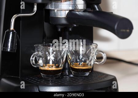 Processo di preparazione di due shot di espresso con la macchina espresso. Caffè italiano. Foto Stock