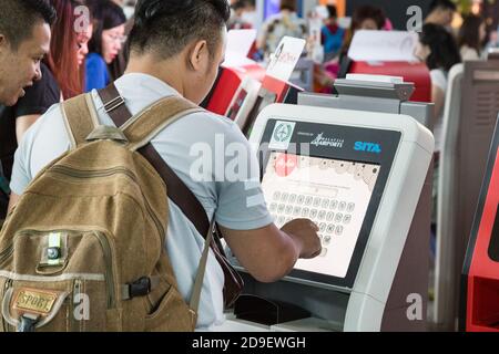 I passeggeri che utilizzano un comodo chiosco per il check-in self-service presso l'aeroporto internazionale di KL per effettuare il check-in del volo. Foto Stock