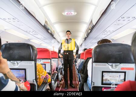 Una serie di steward che dimostrano la prosedure di sicurezza prima del volo aereo commerciale AirAsia decolto. Foto Stock