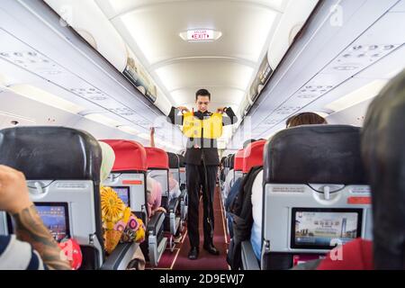 Una serie di steward che dimostrano la prosedure di sicurezza prima del volo aereo commerciale AirAsia decolto. Foto Stock