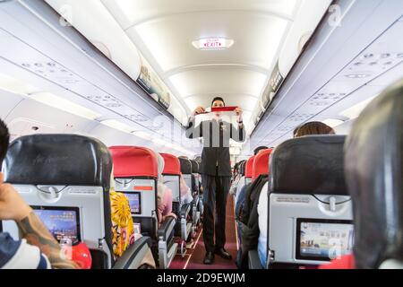 Una serie di steward che dimostrano la prosedure di sicurezza prima del volo aereo commerciale AirAsia decolto. Foto Stock