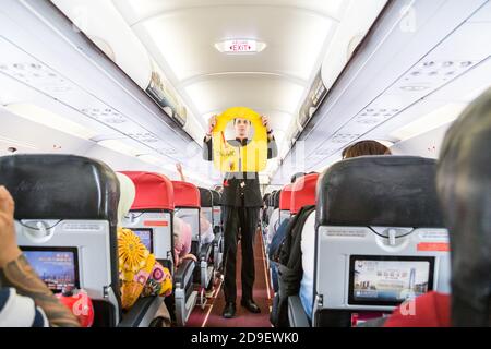 Una serie di steward che dimostrano la prosedure di sicurezza prima del volo aereo commerciale AirAsia decolto. Foto Stock