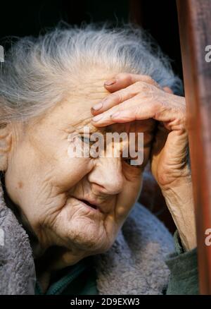Ritratto di un molto vecchio e stanco di vita rugosa donna all'aperto con una mano vicino al viso Foto Stock