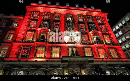 L'esterno del negozio è bagnata di luce rossa e decorata come un calendario festoso dell'avvento.Piccadilly Department store Fortnum & Mason è famoso in tutto il mondo e conosciuto come 'il Grocer della Regina', dopo avere un documentario televisivo su di esso. Rinomato per i suoi prodotti di lusso, ogni anno è orgoglioso dell'illuminazione e della decorazione del grande negozio per il Natale. Quest'anno non è diverso nonostante il blocco di un mese in Inghilterra dovuto Covid-19. Foto Stock