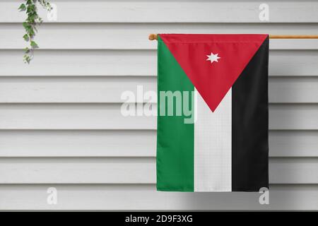 La piccola bandiera della Giordania è appesa a una recinzione per picnic lungo il muro di legno in una città rurale. Concetto di giorno di indipendenza. Foto Stock