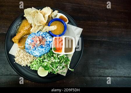 Nasi Kerabu con pollo e cordiments è popolare cibo malese Foto Stock