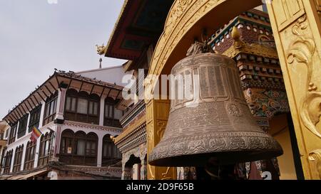 Enorme orologio in metallo montato su un tempio buddista vicino alla famosa Boudhanath stupa (Boudha) a Kathmandu, Nepal. Testo/simboli sull'orologio: Mantra buddisti. Foto Stock