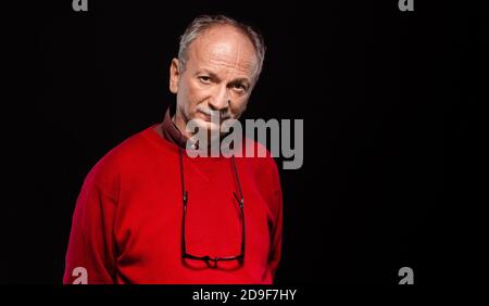 Studio ritratto di un uomo anziano con occhiali in un pullover rosso Foto Stock