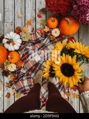 Vista dall'alto della donna dalla vita in giù tenendo i fiori con oggetti autunnali Foto Stock