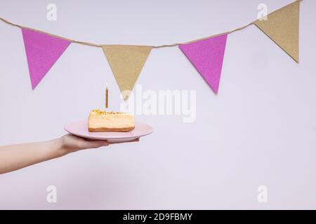 Mano che tiene un pezzo di torta di compleanno Foto Stock