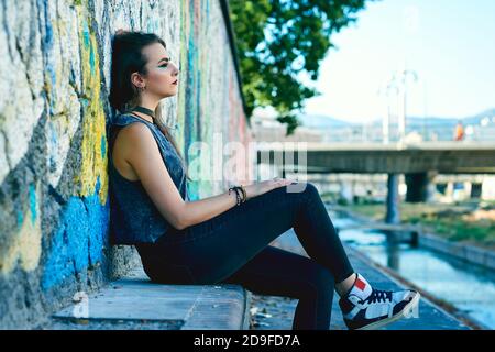 Giovane donna con stile urbano in posa per strada. Foto Stock