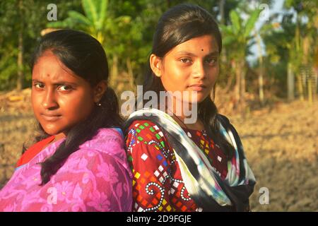 Due belle ragazze indiane adolescenti bengalesi che indossano sari salwar kameez e gioielli dorati come orecchini nasello e in piedi indietro indietro Foto Stock