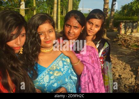 Primo piano di quattro belle ragazze Bengalesi indiane adolescenti con lunghi capelli scuri che indossano sari e gioielli come collana di orecchini dorati, fuoco elettivo Foto Stock