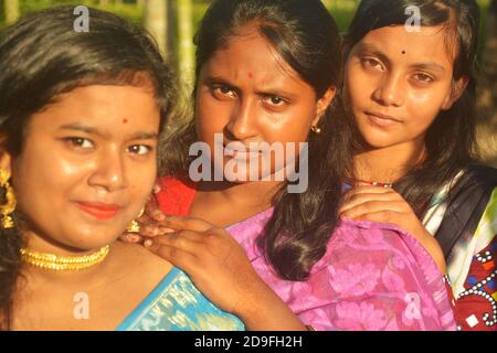 Primo piano di quattro belle ragazze Bengalesi indiane adolescenti con lunghi capelli scuri che indossano sari e gioielli come collana di orecchini dorati, fuoco elettivo Foto Stock