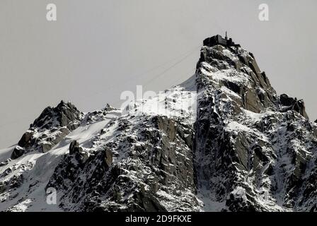 La funivia verticale più alta del mondo impiega solo 20 minuti per salire fino alla cima di 12,605 m dell'Aiguille du Midi, nel massiccio del Monte Bianco, alta Savoia, Auvergne-Rhône-Alpes, Francia, dalla città di Chamonix, che offre una vista superba sulle Alpi francesi e italiane. Dalla cima, un'altra funivia collega la Francia e l'Italia, viaggiando sopra il tunnel del Monte Bianco e la frontiera fino alla vetta di 11,358 m di Pointe o Punte Helbronner. Foto Stock