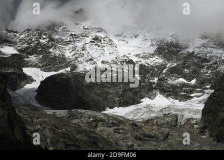 Un'estate alpina sul massiccio del Monte Bianco. Nel mese di agosto, l'acqua di meltwater calpita i canali e le fessure nella roccia striata sotto i campi innevati di alta quota e la fine dei ghiacciai che si snodano lungo le aspre pendenze. Immagine catturata da vicino a Entrèves, Courmayeur, Valle d’Aosta, Italia, vicino all’ingresso italiano del tunnel del Monte Bianco, che dal 1965 ha fornito un collegamento stradale tra Francia e Italia per 11.6 km (7.25 m). Foto Stock