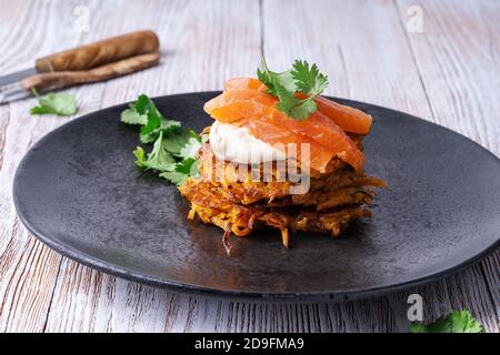 Frittelle di patate dolci con hummus, salmone affumicato e pistacchi su tavola di legno rurale Foto Stock